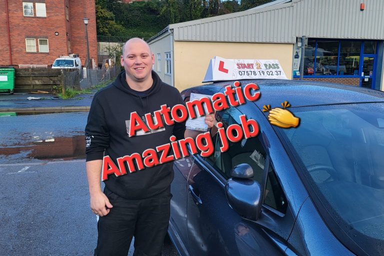 A smiling man stands beside a car, promoting automatic driving lessons.