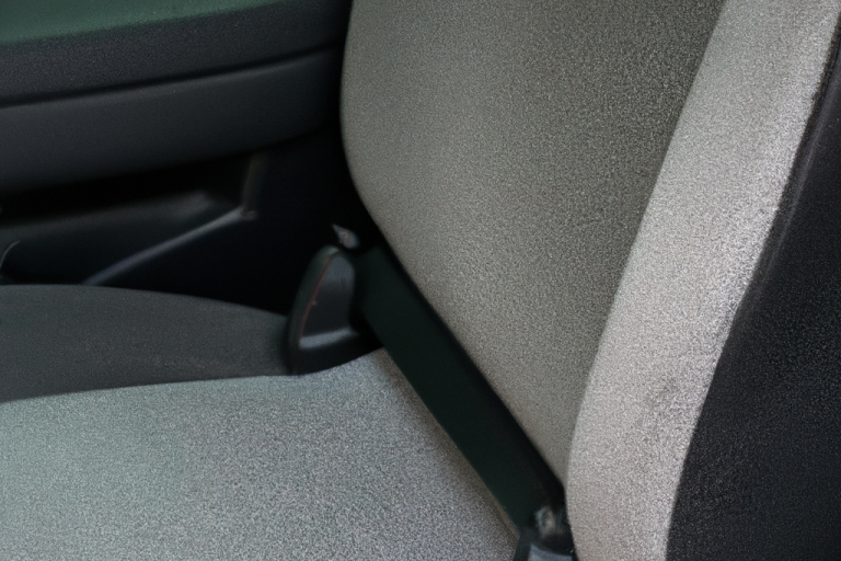 A close-up of a car seat showing the fabric and seatbelt mechanism.