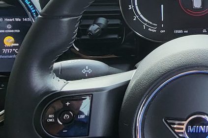 Close-up of a car's steering wheel with a digital display and controls.