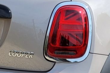 Close-up of a car's rear light, featuring a red lens and chrome accents.