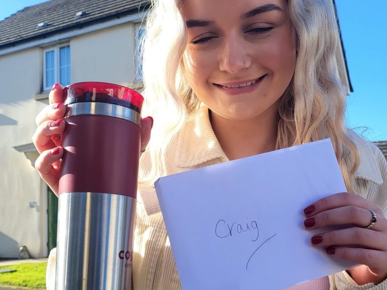 Smiling person holding a coffee mug and a note with "Okay" written on it.