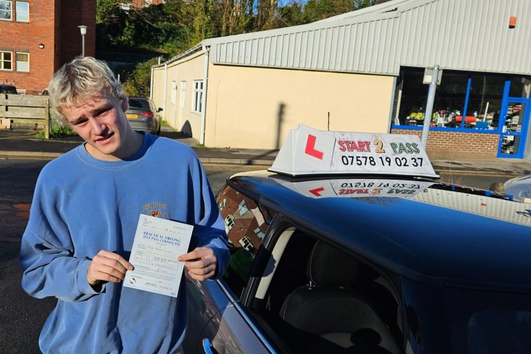 Young person holding a driving test certificate beside a learner driver car.