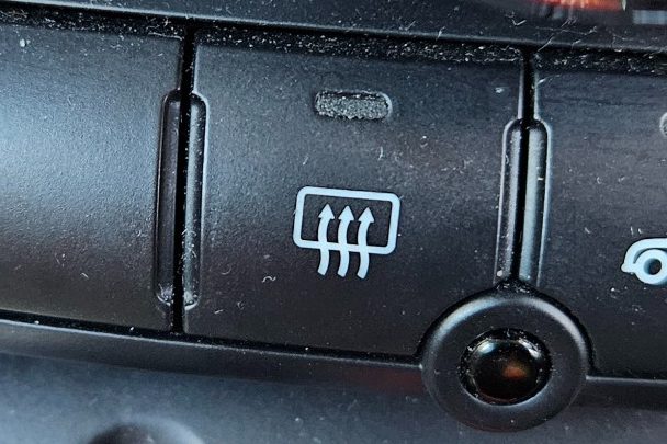 Button for rear window defrost, featuring three horizontal lines and an indicator light.