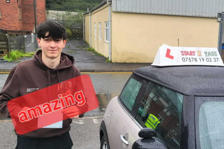 A smiling learner driver holding a sign that says "amazing" next to a car with an L-plate.