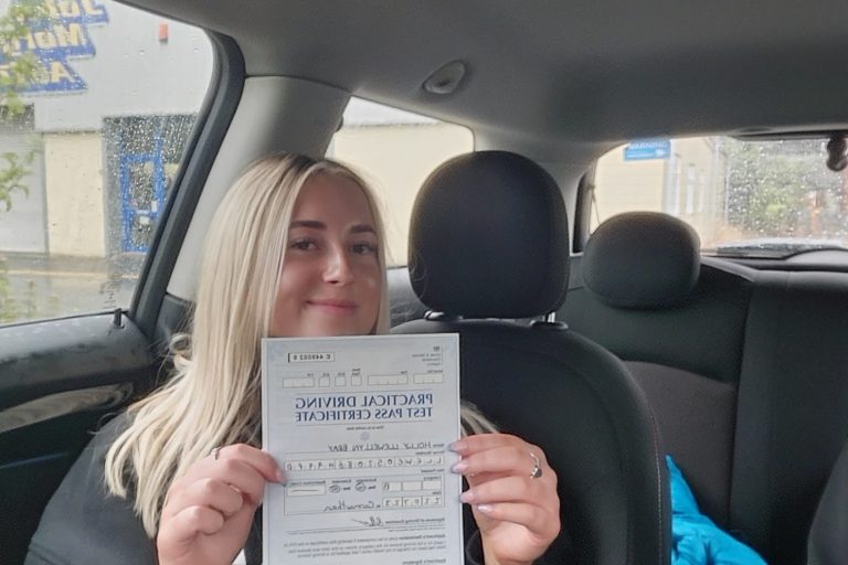 Smiling person holding a document while sitting in a car.