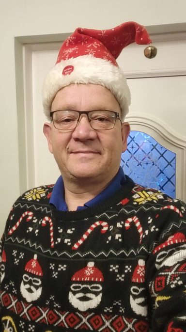 Man wearing a Santa hat and a festive Christmas sweater.